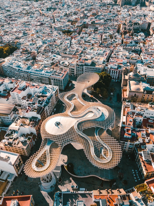 Aerial view of Seville showing the Metropol Parasol, a modern wooden structure with wavy shapes, surrounded by city buildings—an architectural highlight representing the Best of Spain and Portugal.