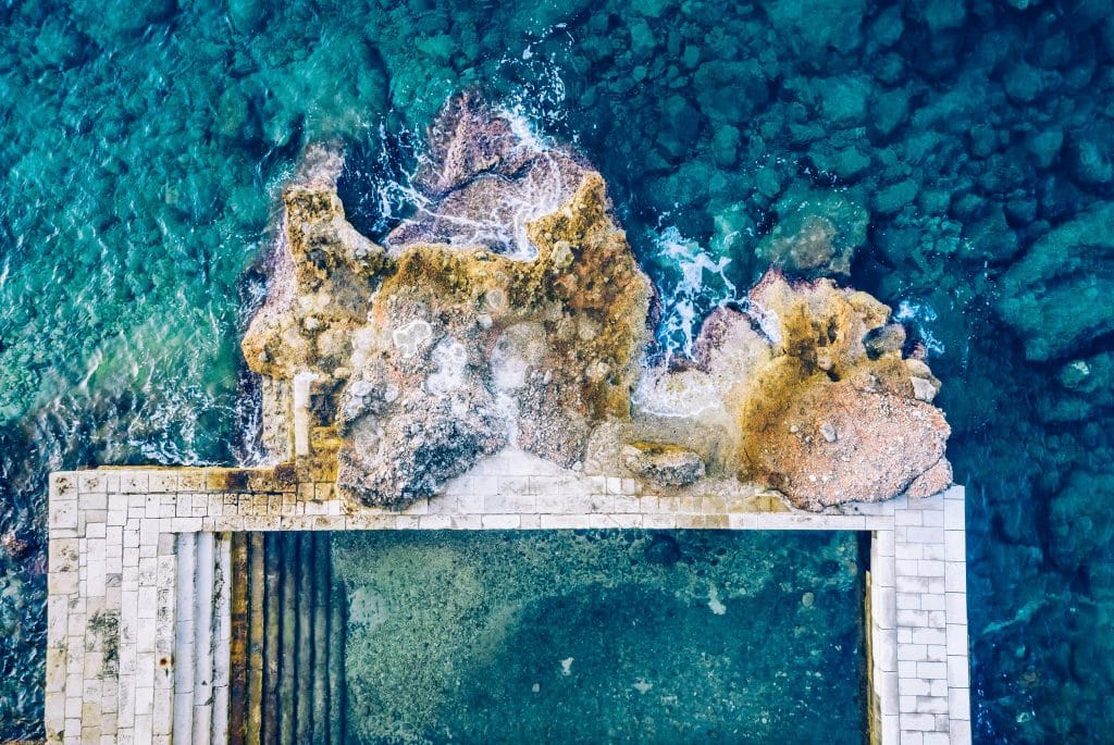 Top-down view rocky beach and clear blue water background.Beach located on the Adriatic sea coastline, Dubrovnik