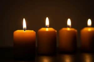 Group of lit candles in a row burning in the darkness
